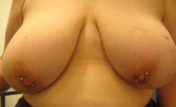 Large-breasted woman with diagonal nipple piercings