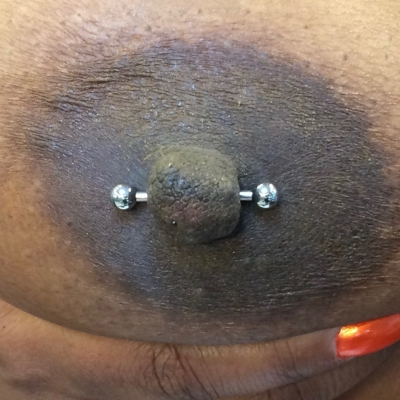 A female nipple piercing with barbell showing sufficient room for expansion and swelling