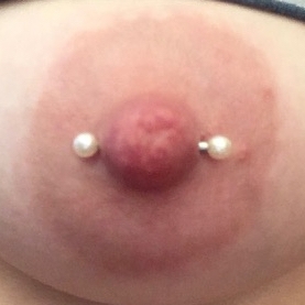 Female nipple piercing with white pearl barbell