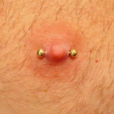 Barbell in a male nipple piercing with gold balls